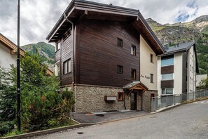 Ein zweistöckiges Gebäude mit Steinuntergrund und dunkler Holzfassade.