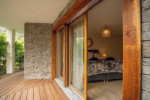 Ein Zimmer mit Steinwand, Holzdielenboden, einem Bett mit gemustertem Überwurf und einer hängenden Leuchte.