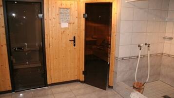 Une porte en bois avec une pancarte, un espace de douche carrelé et un pommeau de douche visible.