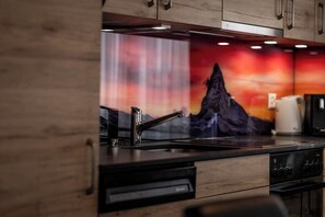 Eine Küche mit modernem Design, ausgestattet mit einer Edelstahl-Spüle, einer Kaffeemaschine und einem Holzkorpus.