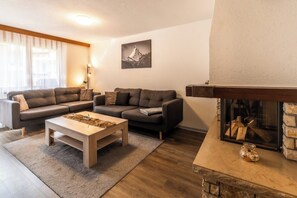Ein modernes Wohnzimmer mit Kamin, einer Sofagarnitur und einem Couchtisch.