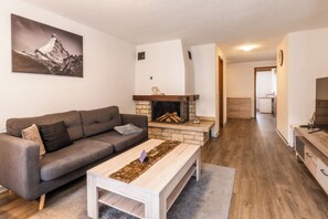 Una sala de estar con un sofá, una mesa de centro, una chimenea y un cuadro en la pared.