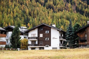 Ein Chalet mit Balkon, eingebettet in eine bewaldete Berglandschaft.