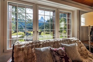 A room with a large window, a fur-covered sofa, and a lamp.