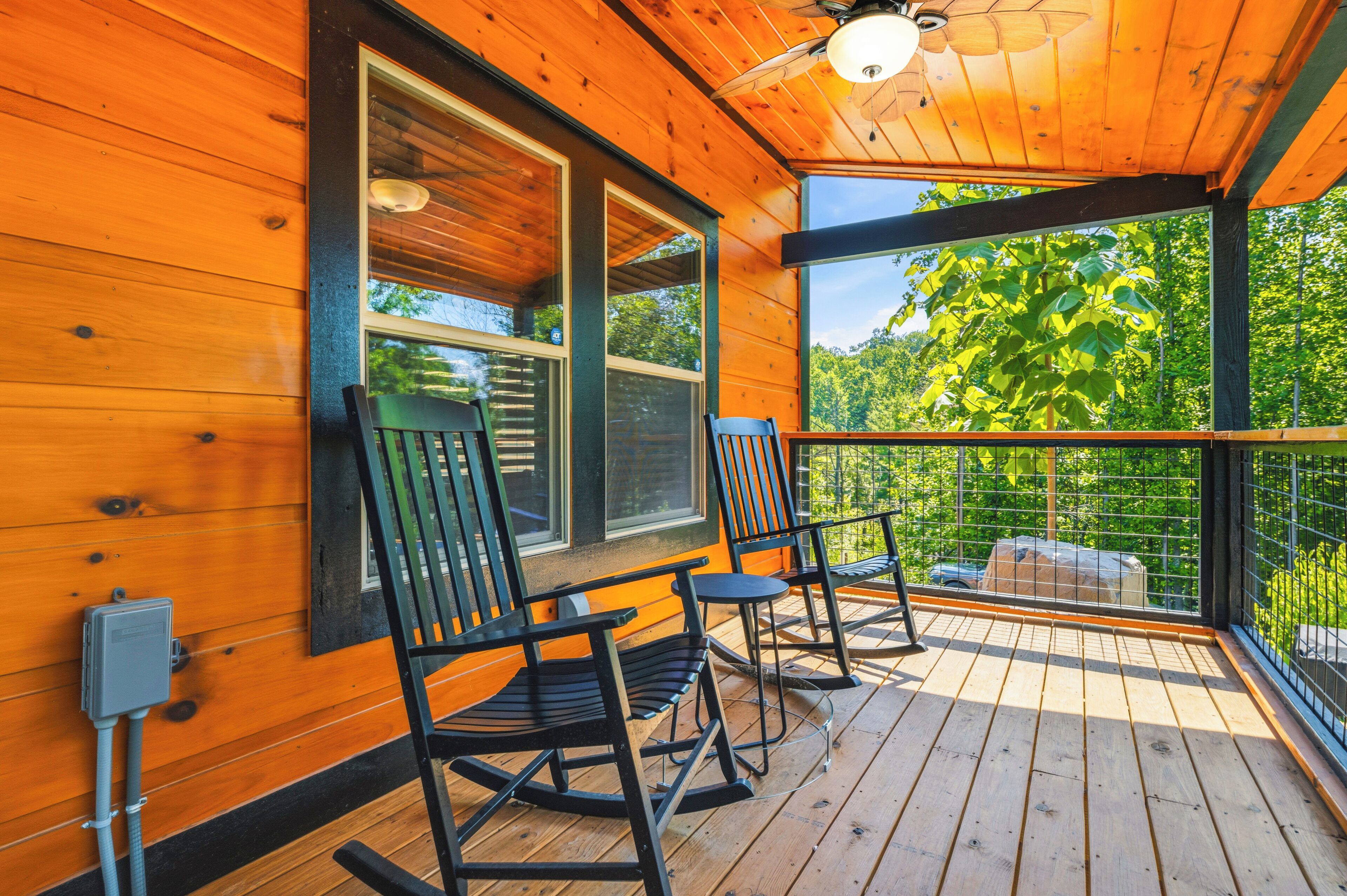 A wooden deck with two rocking chairs and a view of a forest.
