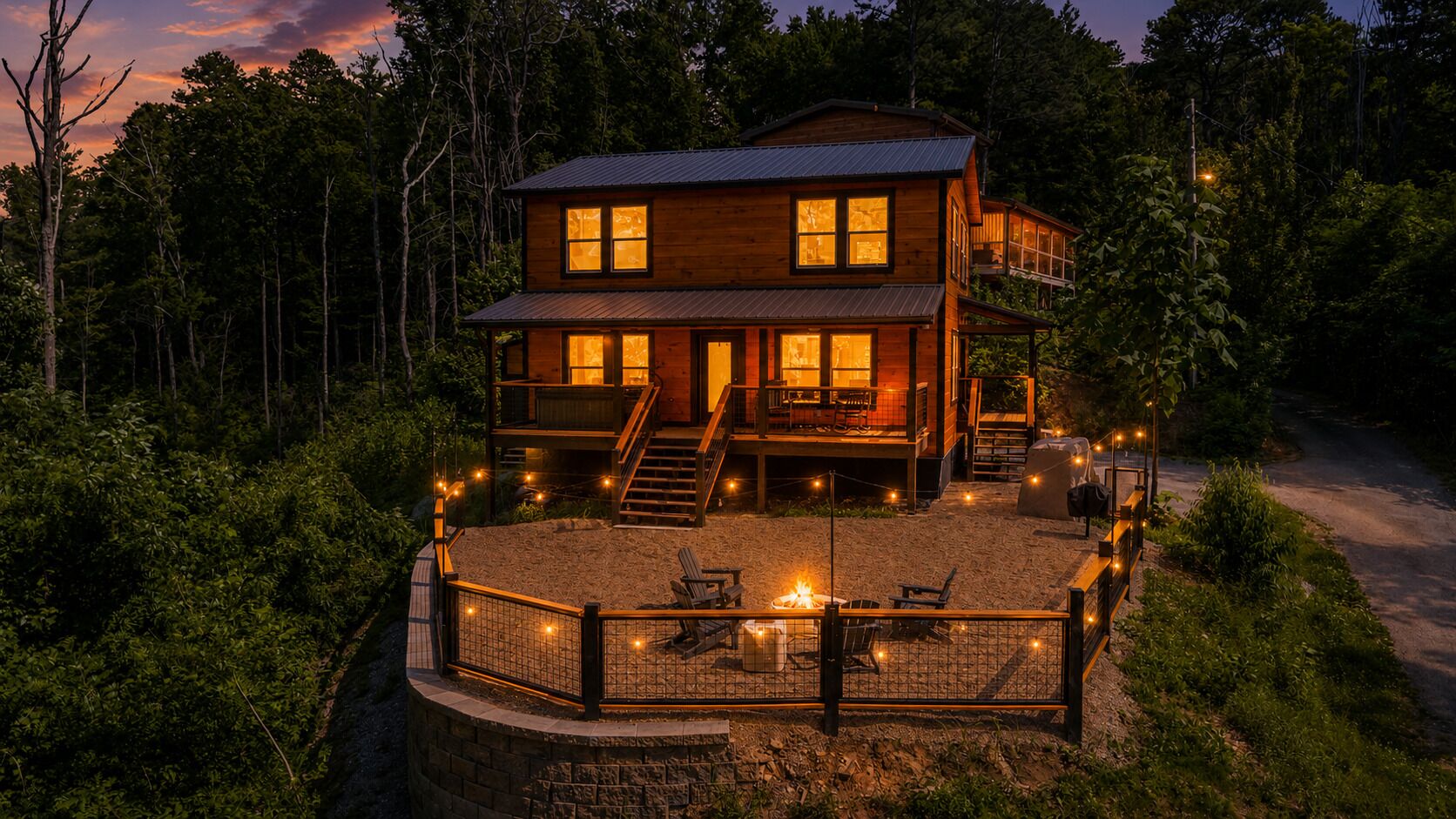 A two-story wooden cabin with a deck, surrounded by dense forest.