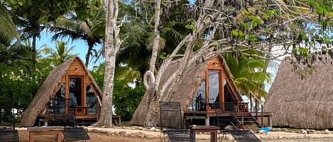 A beachfront property with thatched-roof cabins, clear waters, and lush tropical vegetation.