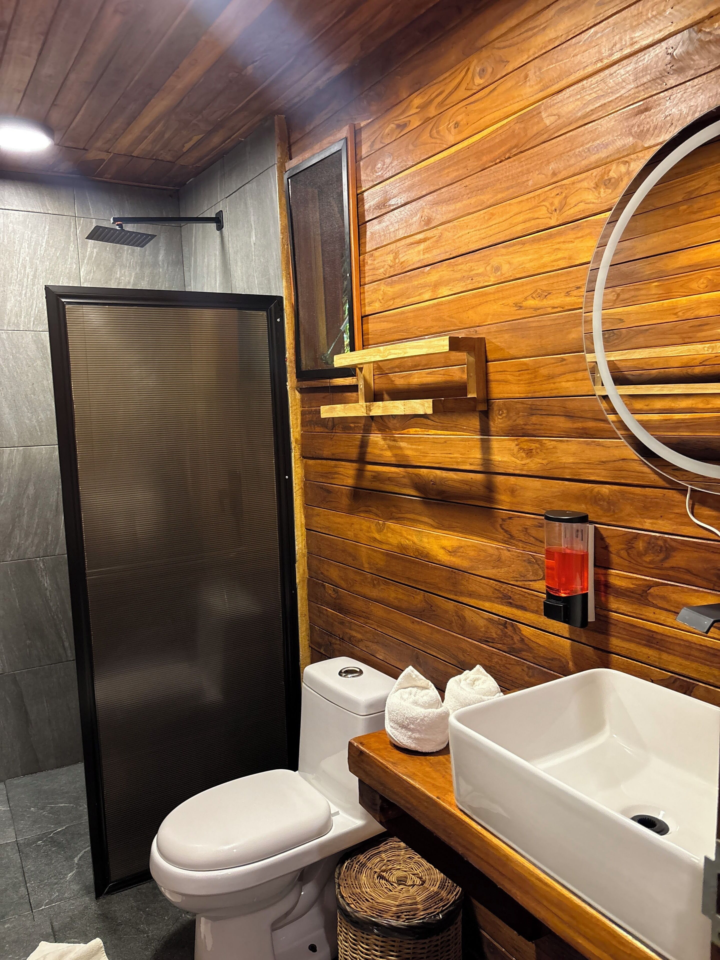 Un bagno con parete in legno, un water bianco, un lavandino bianco e un portasciugamani.