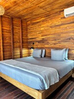 A wooden-paneled room with a bed, a lamp, and an air conditioning unit.
