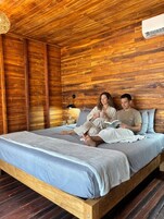 Una habitación de madera con una cama, una mesita de noche y una lámpara.