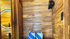 Eine Holzsauna mit zwei Handtüchern auf Regalen und einem Handtuchhalter.