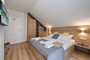 A modern bedroom with a bed, bedside tables, a TV, and a built-in wardrobe. - Spacious villa in Zagorje with jacuzzi, sauna, pool, barbecue, and scenic views (Pregrada)