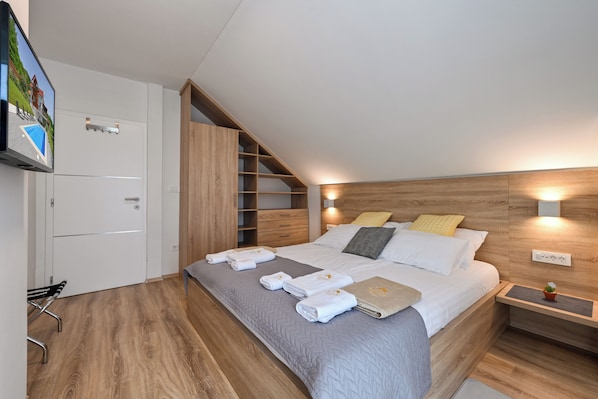 A modern bedroom with a bed, bedside tables, a TV, and a built-in wardrobe.