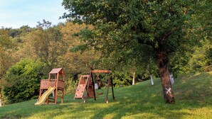 A playground with two wooden play structures, including a slide and swings, set against a backdrop of trees and grass. - Spacious villa in Zagorje with jacuzzi, sauna, pool, barbecue, and scenic views (Pregrada)