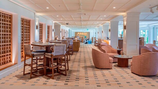 Et hotel lobby med et skakternet gulv, møbler i træ og en receptionsdisk.