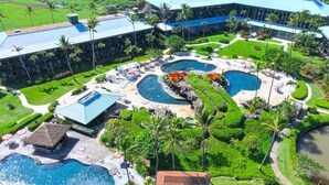 Et resort med flere swimmingpools, frodig beplantning og en stor bygning.