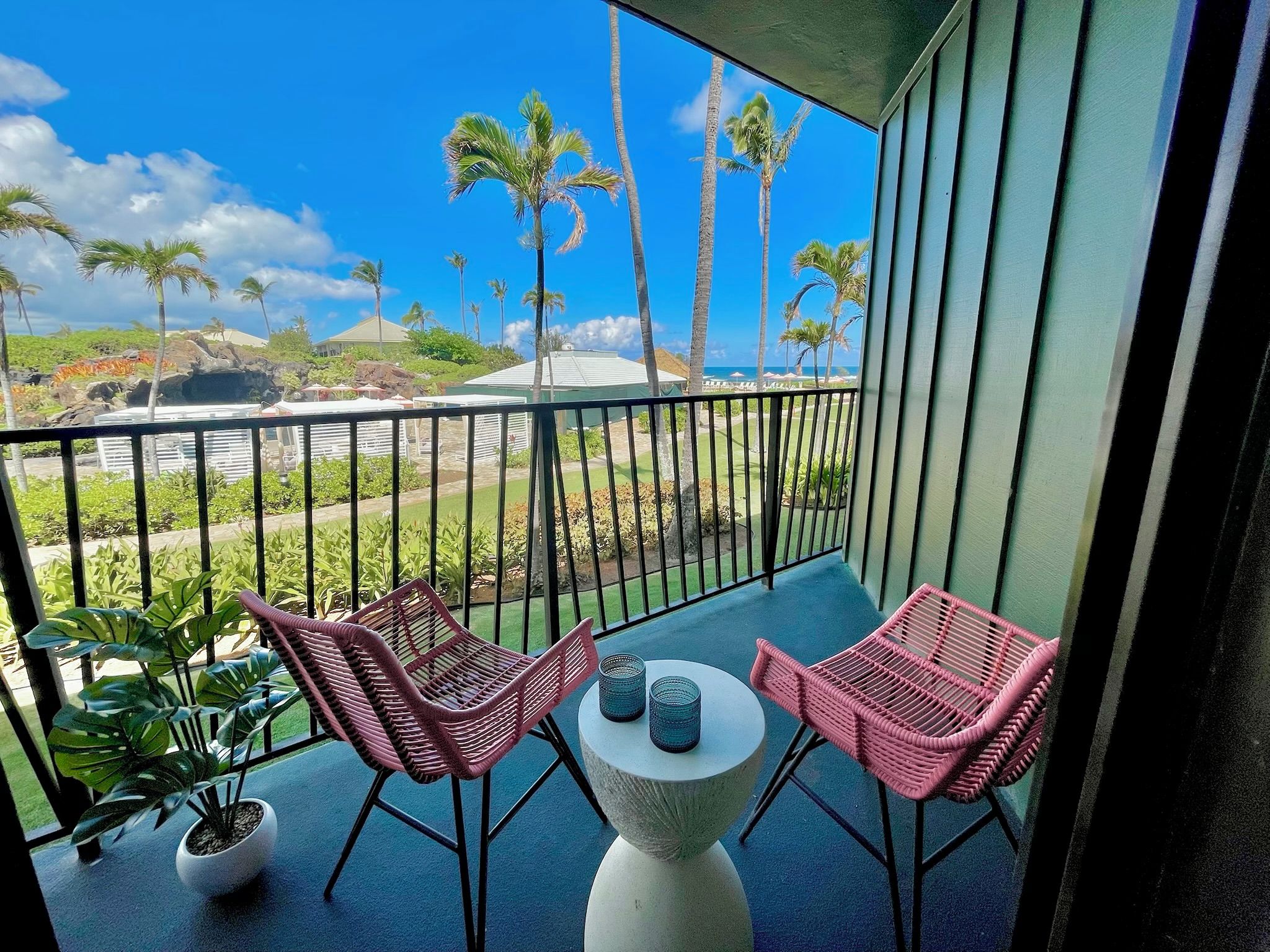A balcony with two wicker chairs, a small table, and a potted plant.