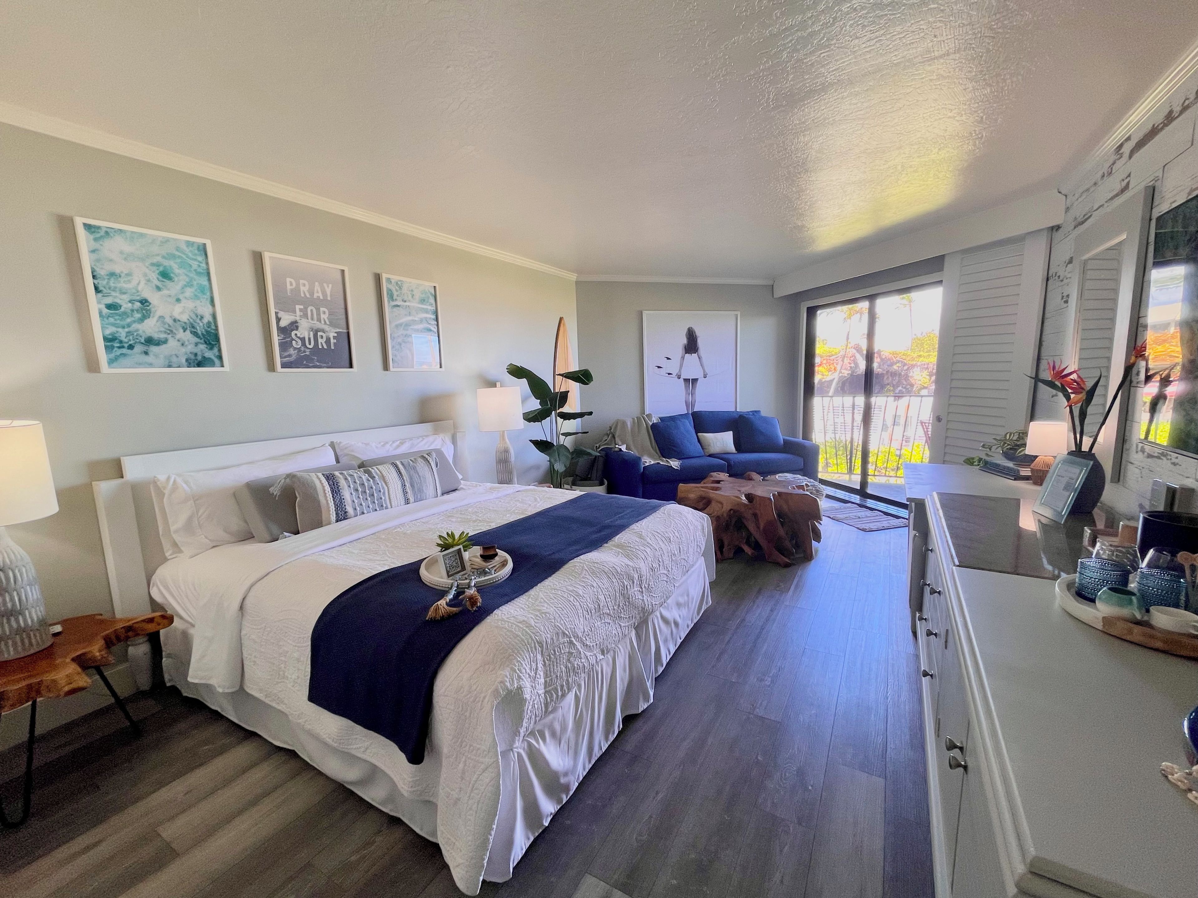 Bright coastal bedroom with king bed, cozy lounge area, natural light from the resort pool and ocean views