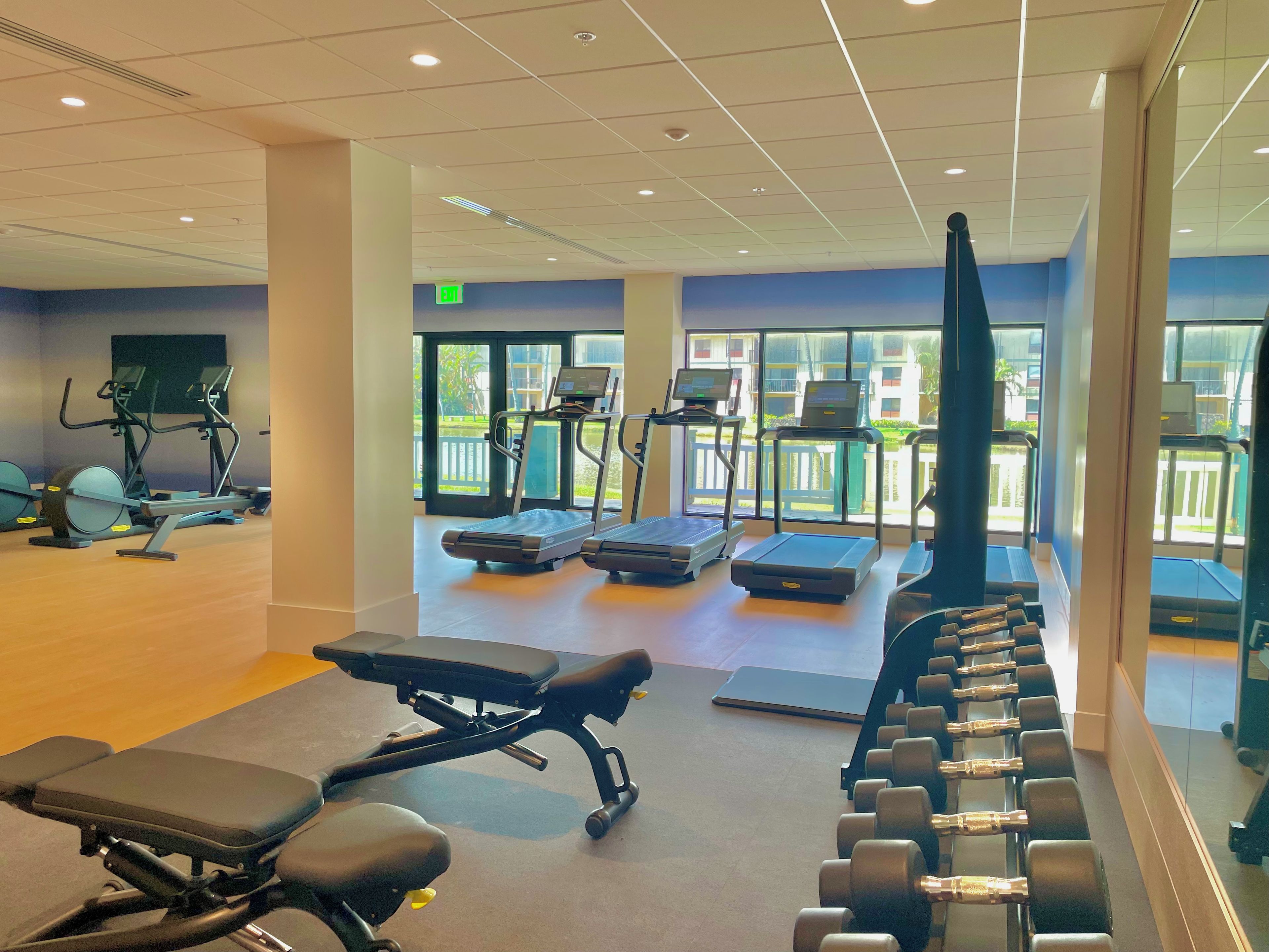 A gym with exercise equipment, a bench, and dumbbells.