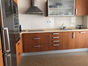 A modern kitchen with wooden cabinets, stainless steel appliances, and a tiled backsplash.