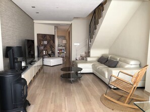 A modern living room with a sofa, a coffee table, a television, and a bookshelf.