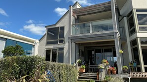 A modern two-story house with a balcony, large windows, and a well-maintained garden. - Absolute beachfront in Waiwera (Waiwera)