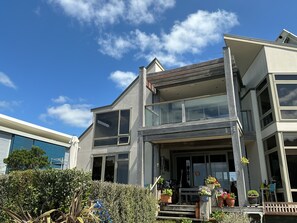 A modern two-story house with a balcony, large windows, and a well-maintained garden. - Absolute beachfront in Waiwera (Waiwera)