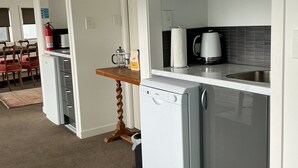 A compact kitchenette with a microwave, a small refrigerator, and a coffee maker. - Absolute beachfront in Waiwera (Waiwera)