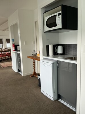 A compact kitchenette with a microwave, a small refrigerator, and a coffee maker. - Absolute beachfront in Waiwera (Waiwera)