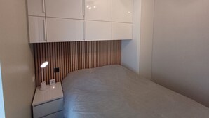 Una camera da letto con un letto, un comodino, una lampada e un armadio.