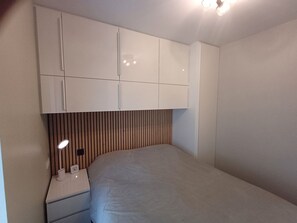 A bedroom with a bed, a nightstand, a lamp, and a wardrobe. - Ein Bungalow in einem Ferienpark, ganz in der Nähe vom Meer by Interhome (Middelkerke)
