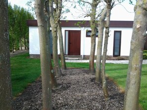A building with a white facade, a brown door, and a small window. - Ein Bungalow in einem Ferienpark, ganz in der Nähe vom Meer by Interhome (Middelkerke)