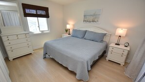 A bedroom with a bed, two bedside tables, a dresser, a window with blinds, and a painting on the wall. - Maritime Place B9 - Oceanfront in Garden City Beach (Garden City)