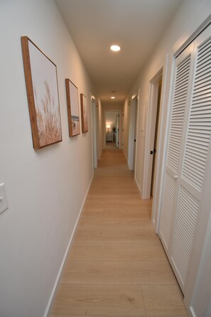 A hallway with wooden flooring, white walls, and a series of doors on one side. - Maritime Place B9 - Oceanfront in Garden City Beach (Garden City)