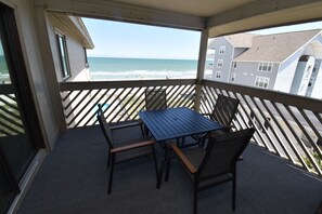 Un balcon avec vue sur la plage et l’océan, comprenant une table et des chaises.
