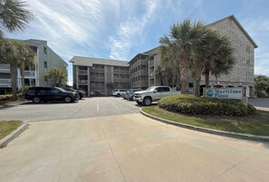 A parking lot with several cars, a building labeled 'Maritime Place,' and a sign with a logo. - Maritime Place B9 - Oceanfront in Garden City Beach (Garden City)
