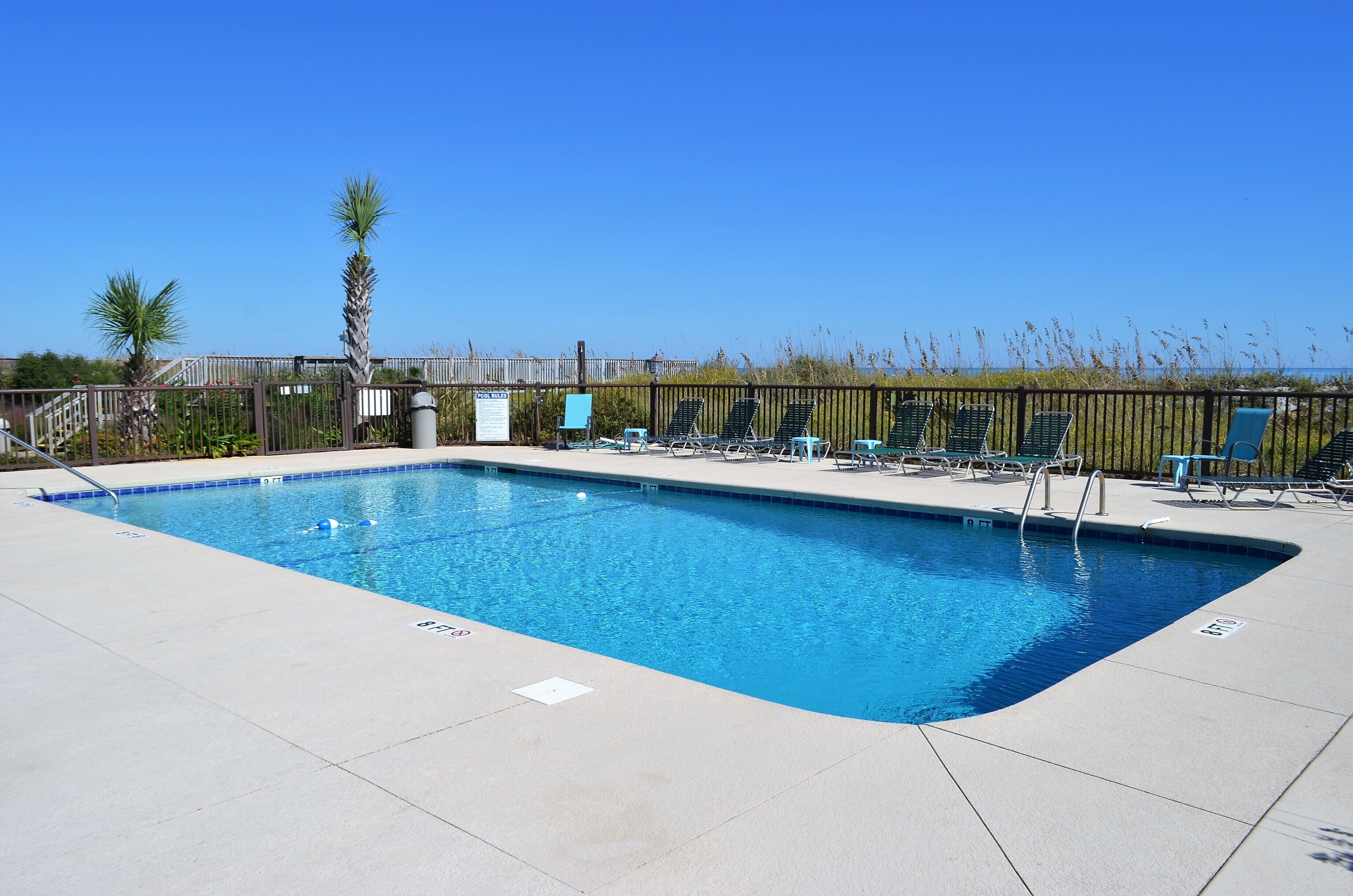 A rectangular swimming pool with a clear blue water surface, surrounded by a tiled deck.