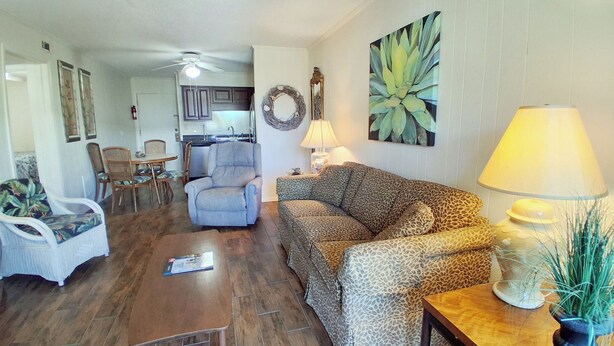 A living room with a sofa, armchair, dining table, and a kitchen in the background. - South Pointe Villas 6 - Oceanfront Complex (Oceanview Unit) in Garden City Beach (Garden City)