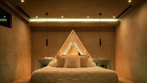 Un dormitorio moderno con una cama grande, mesitas de noche y una lámpara con diseño geométrico.