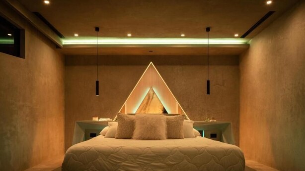 Un dormitorio moderno con una cama grande, mesitas de noche y una lámpara con diseño geométrico.
