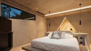 Un dormitorio moderno con una cama grande, mesitas de noche, un televisor integrado y una ventana.