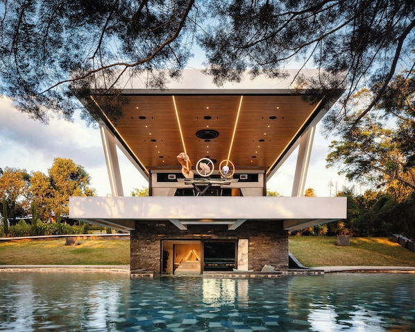 A modern building with a pool in front, featuring a wooden ceiling and stone walls. - Nebulae Boutique Stay (San Roque)