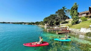 Un lago tranquilo con kayaks, un muelle y una zona verde con árboles.