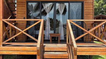 A wooden deck with a staircase leading to a building with large windows and a view of palm trees.