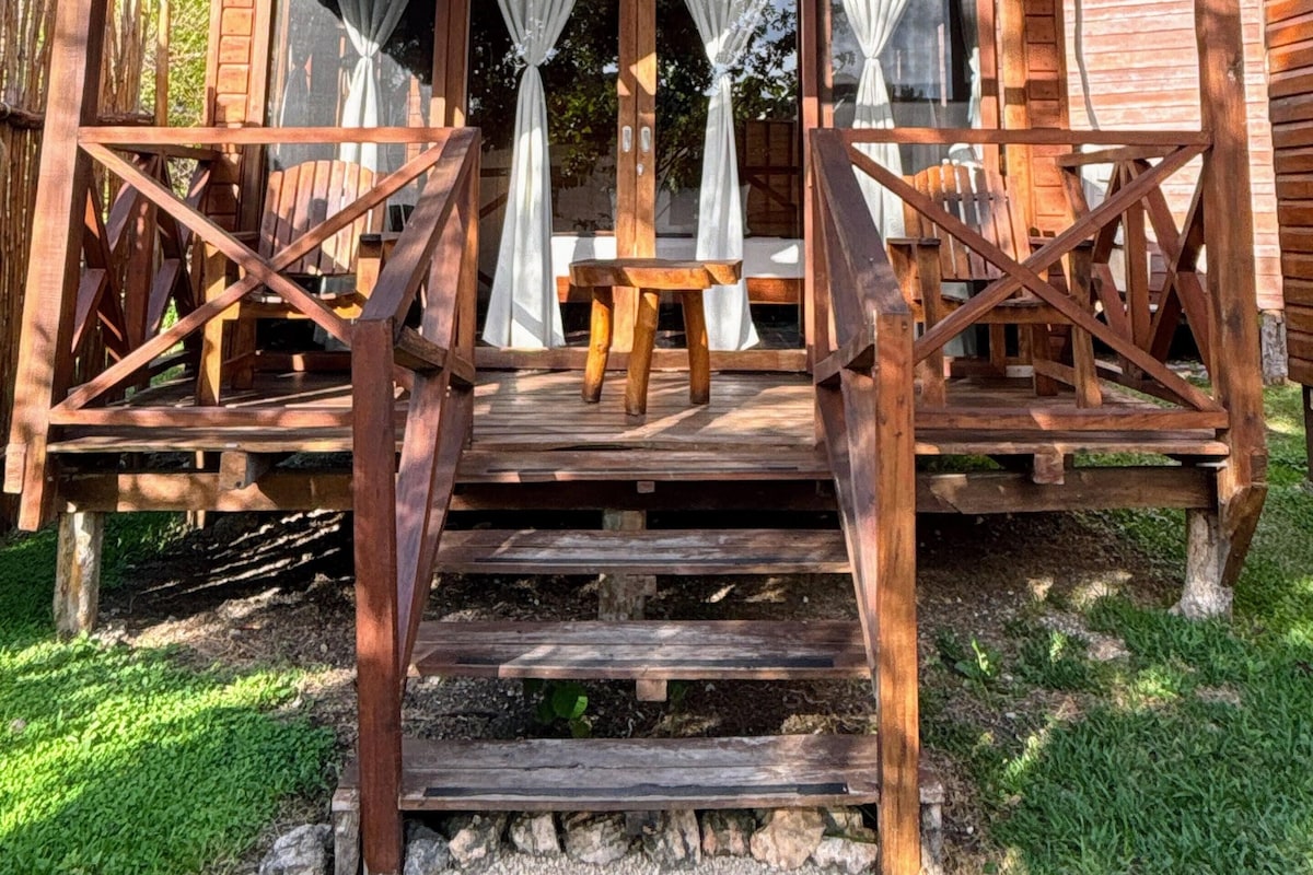 Eine Holzkonstruktion mit Veranda, Tisch und Stühlen.