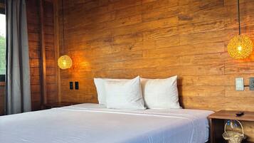 A wooden-paneled room with a bed, two wall-mounted air conditioners, and two hanging light fixtures.