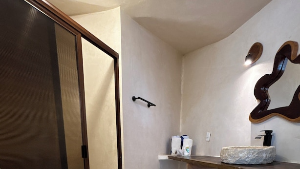 Une salle de bain comprenant des toilettes, une douche, un lavabo avec un receveur en pierre et un porte-serviettes.