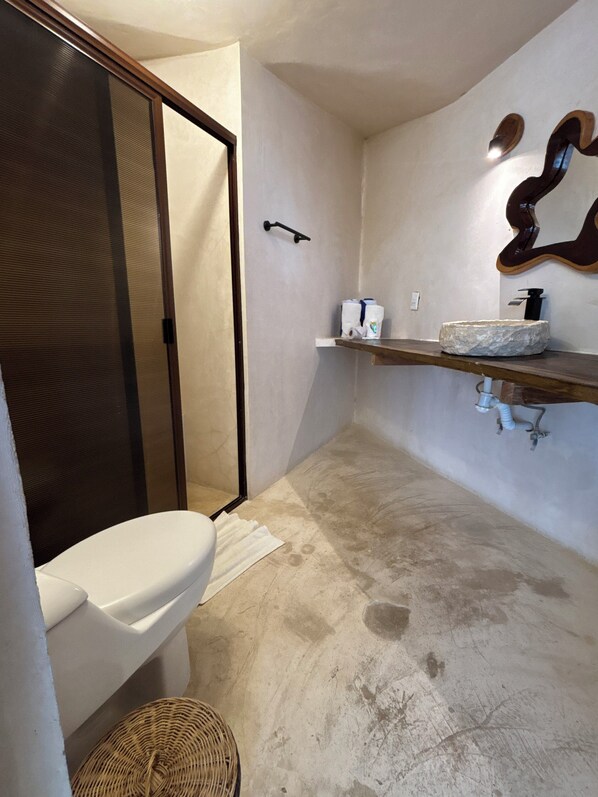 Ein Badezimmer mit Toilette, Dusche, Waschbecken mit Steinbecken und Handtuchhalter.