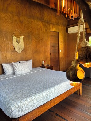 A wooden bed with a patterned bedspread, a macrame wall hanging, and a hanging light fixture. - Hotel My Love Bacalar Lagoon Front - Free Kayak Rental (Bacalar)