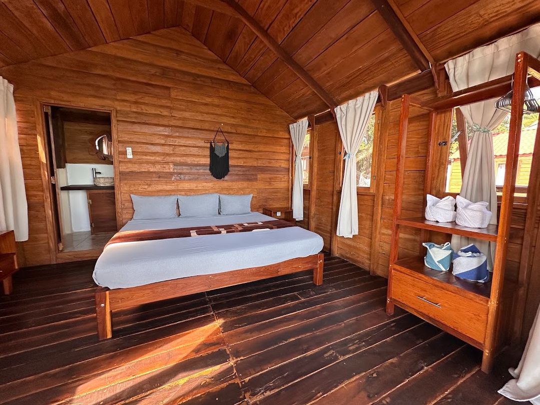 Un dormitorio de cabaña de madera con cama, armario y una pequeña cocina.